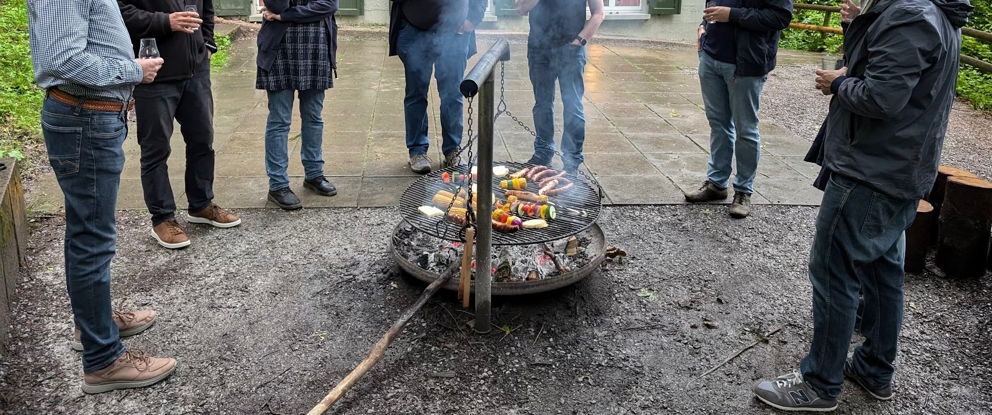 Mehrere Personen stehen um eine Feuerstelle herum